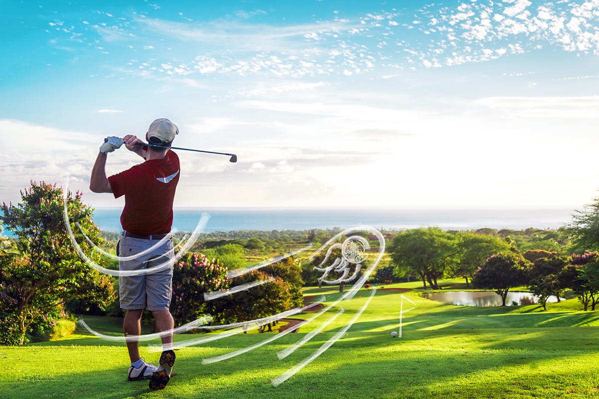 Man swinging his golf club in a golf course surrounded by the ocean.