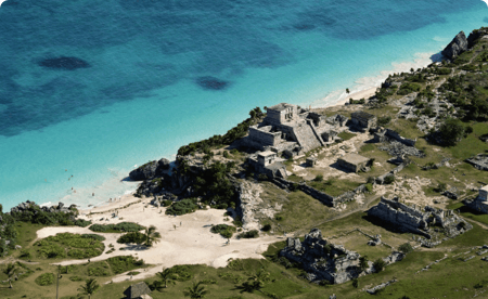Birds-eye view of ancient ruins next to a pristine beach.