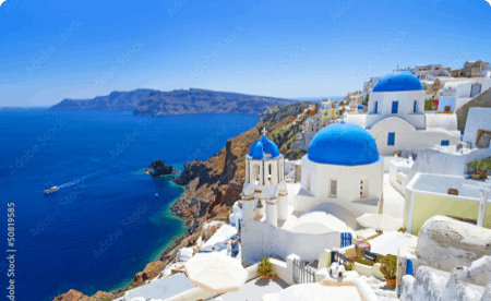The coast of a Greek island, with buildings with characteristic blue roofs, overlooking blue seas.