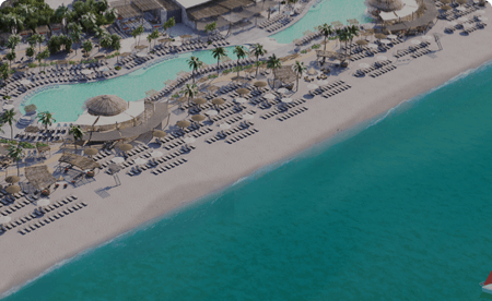 Overhead view of a turquoise ocean next to lines of beach chairs. Behind the beach chairs are two lagoon-shaped pools surrounded by more chairs and palm trees.